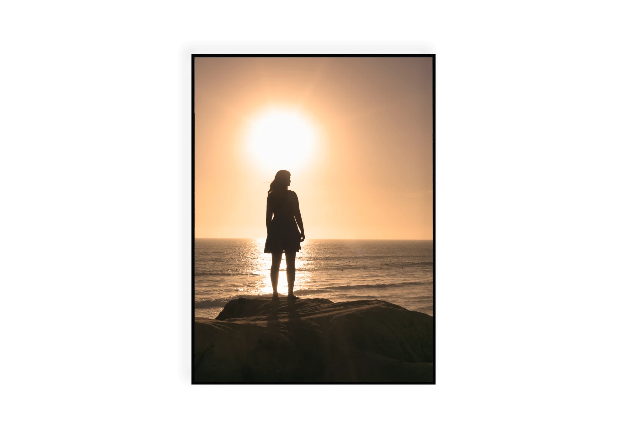 Photographie d'une femme debout sur une falaise regardant le ciel durant un coucher de soleil.