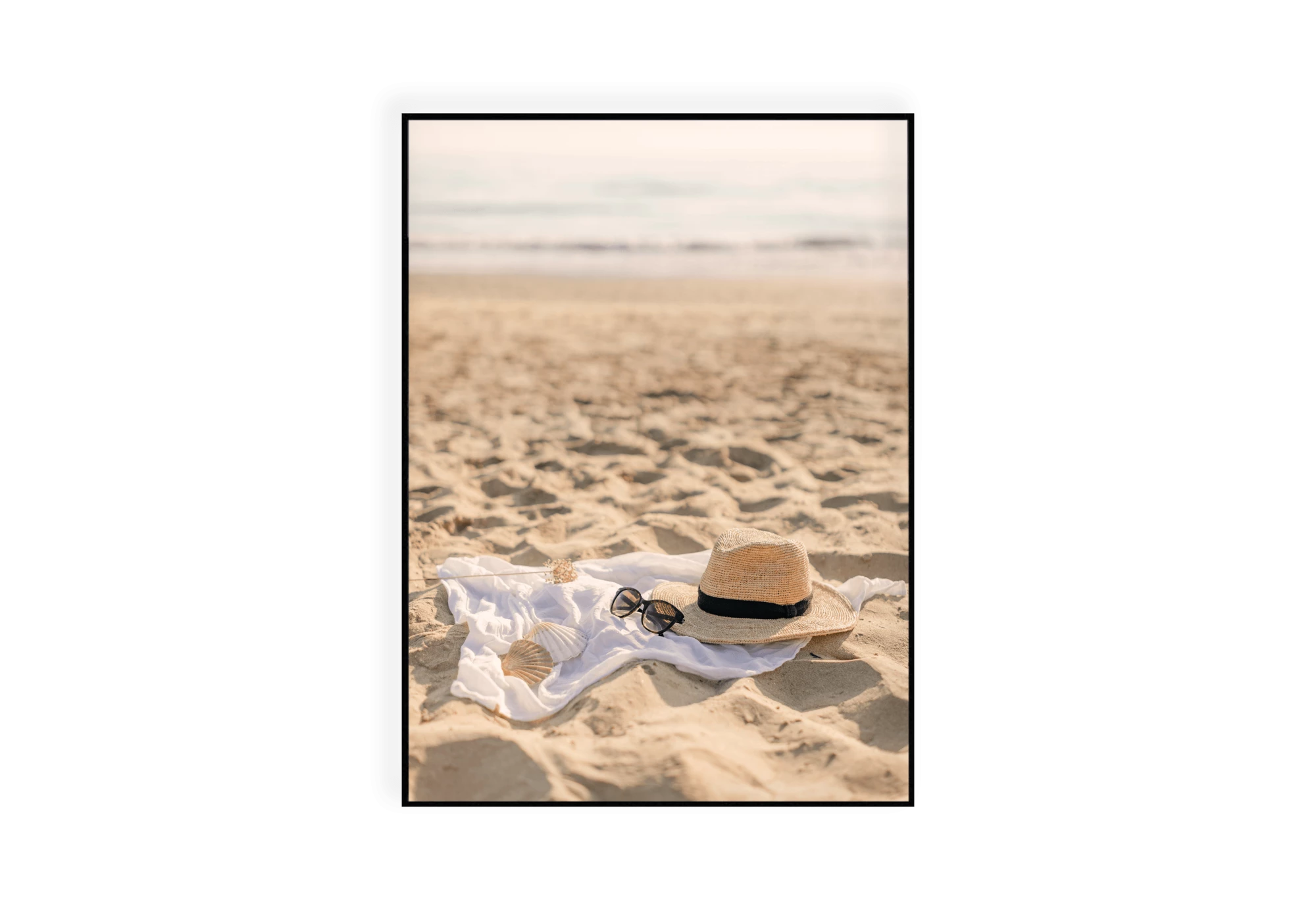 Photographie d'un chapeau, d'une paire de lunettes et de coquillages dans le sable
