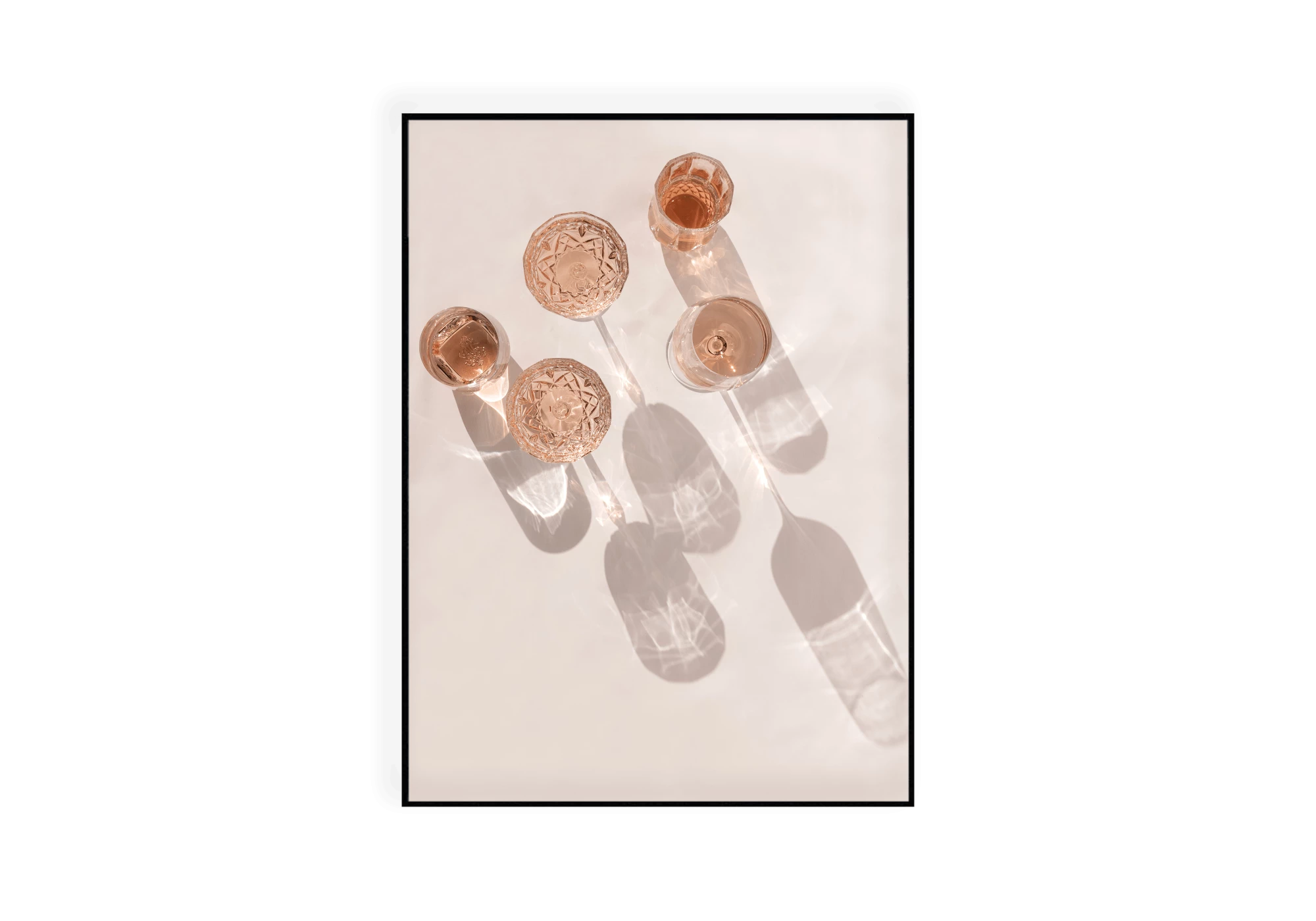 Photographie vue de haut montrant plusieurs verres de rosés sur le sable de la plage.