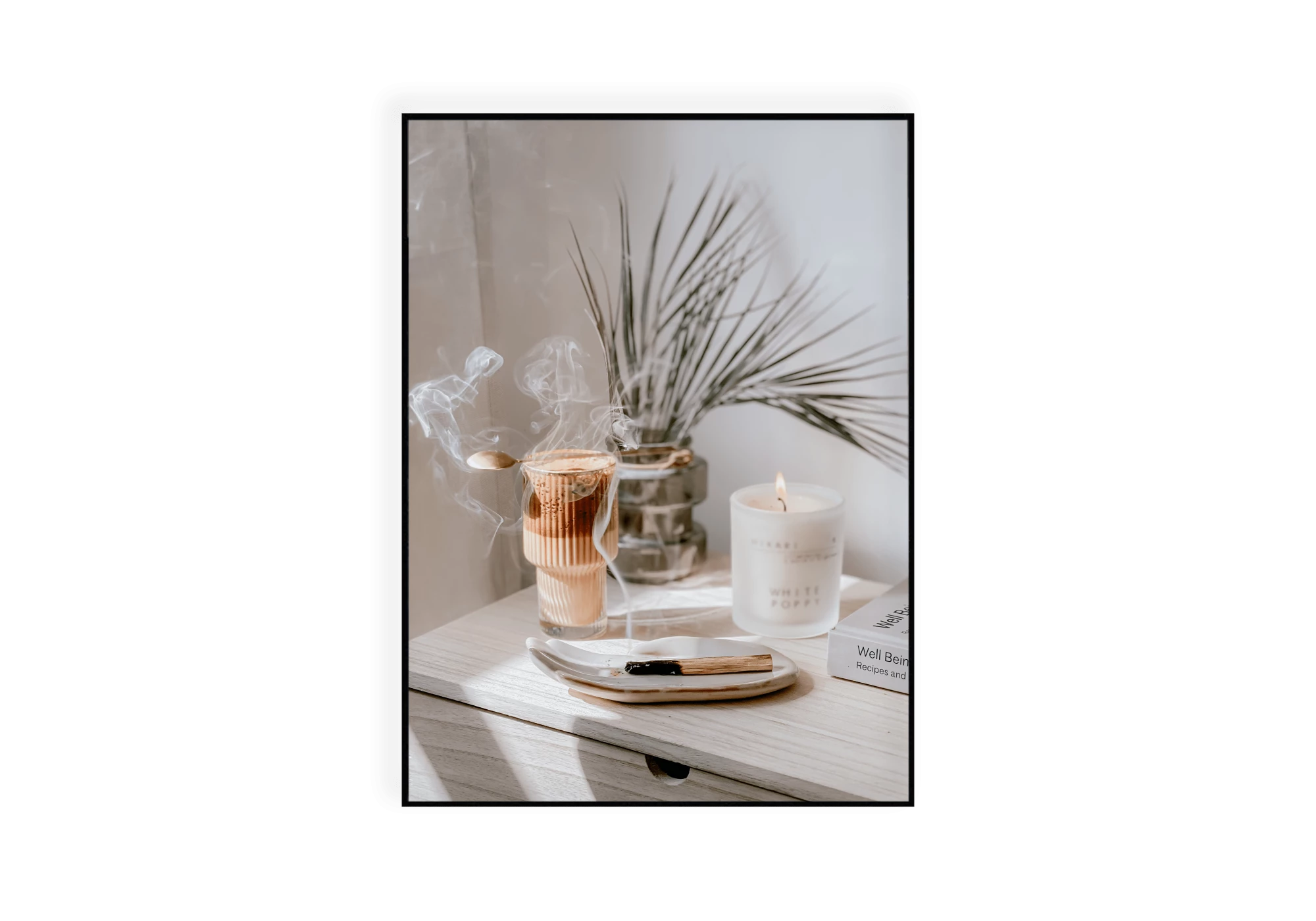 Photographie d'un meuble où sont posés une bougie et de l'encens qui brûlent, un livre, une plante et un chocolat chaud.