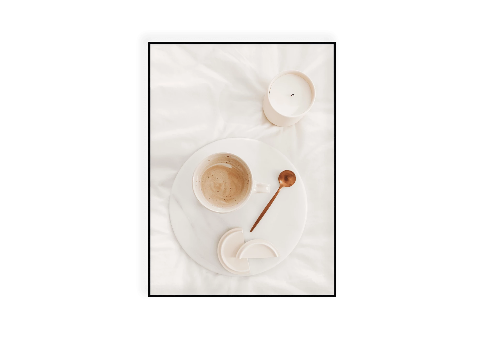 Photographie d'une tasse de café et sa cuillère sur une assiette et d'une bougie posée sur des draps blancs.