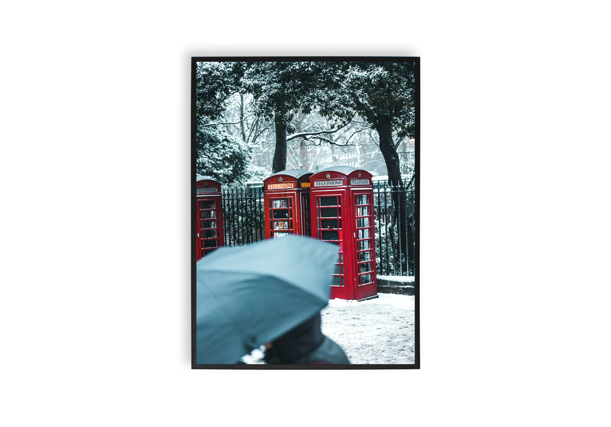 Affiche artistique représentant des cabines téléphoniques rouges emblématiques, sous la neige, parfait pour décorer l'intérieur de votre maison. Ce cadre apporte une touche d'élégance et d'originalité à vos murs, tirant parti du contraste entre le rouge vibrant et le paysage hivernal.